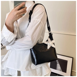 Détail de sac seau en cuir verni noir avec pendentif étoile argenté et texture plissée