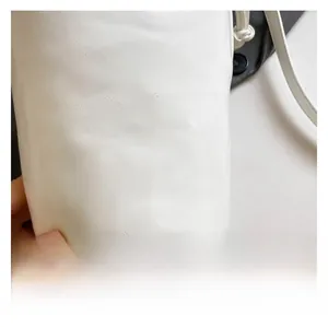 Détail du sac seau en cuir blanc avec rivets et texture de surface en cuir grainé