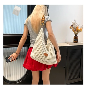 Detail of hand-woven tote bag featuring cream crochet mesh and round wooden bead strap