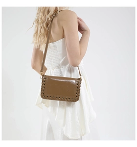 Detail of a brown leather crossbody bag with distinctive woven edges and gold metal buckle