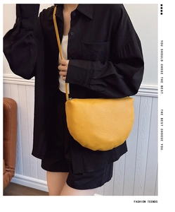 Detail of a bright yellow lychee texture half-moon crossbody bag worn by a model