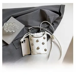 Détail du sac seau blanc avec clous argentés, poignée anneau métal et cordon de serrage