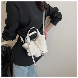 Detailed view of white crocodile pattern mini bucket bag with cute bear charm and strap