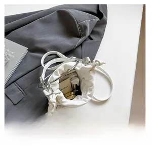 Intérieur spacieux du sac seau blanc à rivets montrant le rangement des cosmétiques