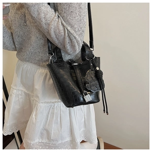 Detail of black bucket bag with crocodile texture and silver clasp on model