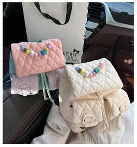 Quilted leather backpacks in pink and cream with colorful beaded handles in a car interior
