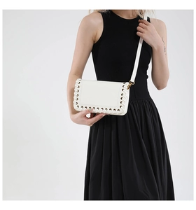 Detailed view of white leather shoulder bag with chic eyelet weaving and golden metal clips