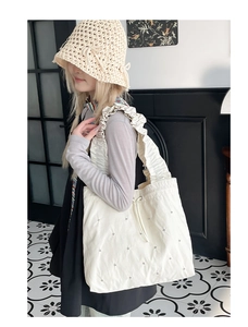 Detailansicht der weißen Schultertasche mit Falten, Metallnieten und Kordelzug am Model