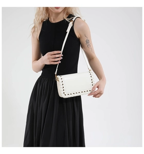 Detailed view of white crossbody bag with unique hollow woven edge and golden clasp