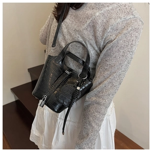 Detail of black crocodile texture bucket bag featuring silver lock and slender strap