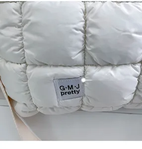 Dettaglio macro del tessuto trapuntato bianco ed etichetta del marchio sulla borsa casual