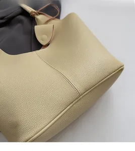 Close-up of beige tote bag showing soft pebble grain texture and handle stitching