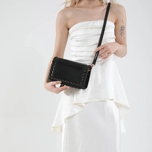 Minimalist black woven crossbody bag with metal eyelet details and shoulder strap
