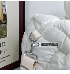 Dettaglio degli anelli a D argento e tracolla staccabile sulla borsa bianca trapuntata
