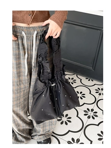 Detail einer schwarzen Rüschentasche mit eleganten weißen Perlenverzierungen für Damen