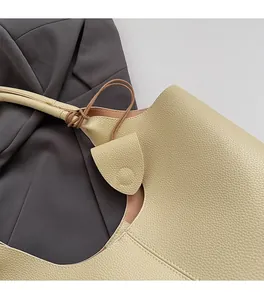 Close-up of cream pebble leather texture and neat stitching on a luxury bucket bag