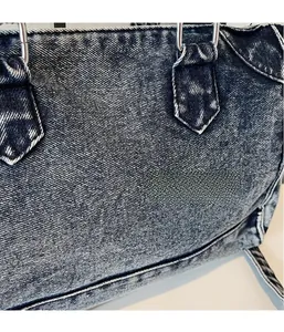 Détail d'un sac cabas en jean vintage avec texture lavée et anneaux métalliques