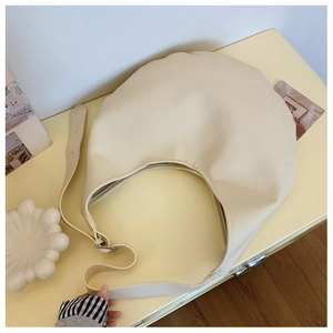 Vue de dessus d'un sac hobo crème avec texture cuir grainé et une large bandoulière