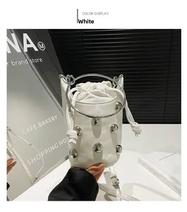 Détail d'un sac seau en cuir blanc avec rivets argentés et grande poignée en anneau métal