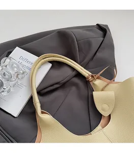 Detail of beige lychee leather bucket bag with wide shoulder strap and knot design