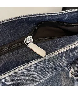 Gros plan sur une fermeture éclair en métal argenté d'un sac cabas en denim bleu