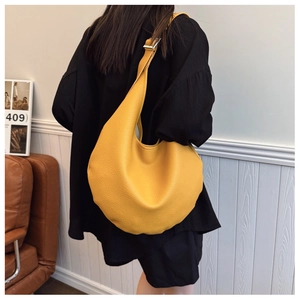 Detail of yellow pebbled leather hobo bag with wide shoulder strap and silver metal buckle