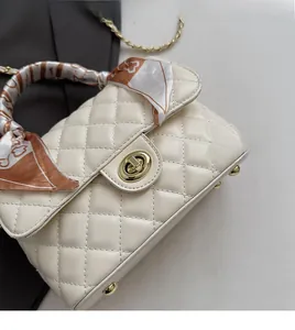 Close-up of beige quilted crossbody bag featuring a golden clasp and silk scarf handle detail