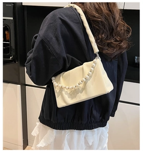 Détail du sac bandoulière plissé crème avec une grande chaîne décorative en perles