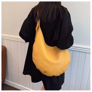 Detail of yellow lychee texture leather shoulder bag showing crescent shape and fine stitching