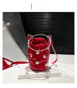 Détail du sac seau rouge orné de rivets argentés et d'une poignée en anneau métal