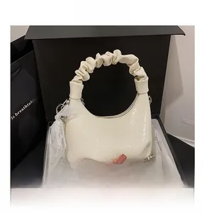 Détail du sac croissant crème plissé avec rubans en dentelle et décoration de chaîne argent