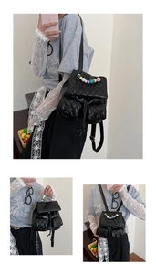 Detail of quilted black leather backpack featuring vibrant colorful bead handle and front pockets