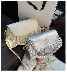 Détail de sacs bandoulière plissés avec poignées en perles et chaînes argentées en voiture