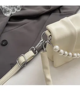 Détail d'un sac en cuir crème avec boucles argentées et chaîne en perles fantaisie