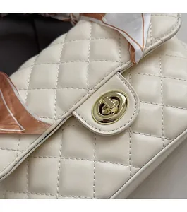 Detail of cream white quilted bag featuring gold rotary lock and floral silk scarf handle