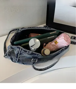 Vue de dessus de l'intérieur spacieux du sac en jean contenant tablettes et parapluie