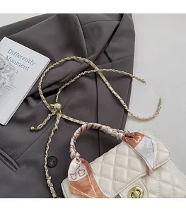 Detail of cream quilted handbag with gold turn-lock and silk scarf wrapped handle