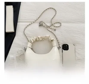 Détail d'un sac nuage en cuir verni blanc avec breloque en perles et bandoulière chaîne