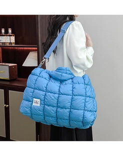 Dettaglio della borsa trapuntata blu brillante con tracolla indossata da una persona