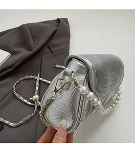 Détail du sac plissé argenté avec poignée en perles et bandoulière dorée