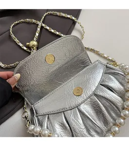 Détail du sac plissé argenté avec fermoirs magnétiques dorés et poignée en perles
