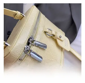 Detail shot of the cream textured leather handbag with silver zippers and metal accents