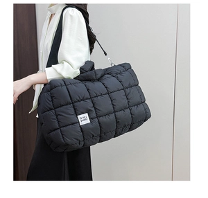 Dettaglio della borsa tote puffer nera con motivi trapuntati ed etichetta di marca