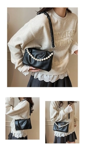 Détail du sac bandoulière noir plissé avec chaîne de perles élégante et texture PU mat