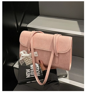 Detailed shot of pink pleated leather bag with a delicate pearl bow charm attachment