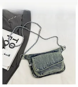 Detail of vintage blue denim crossbody bag with woven chain strap and layered zippers