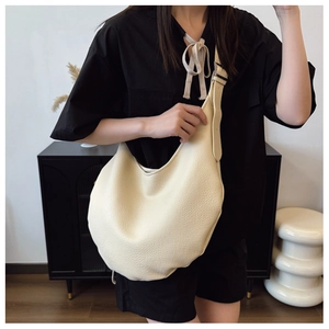 Detailed view of cream leather hobo bag with litchi grain texture and wide shoulder strap