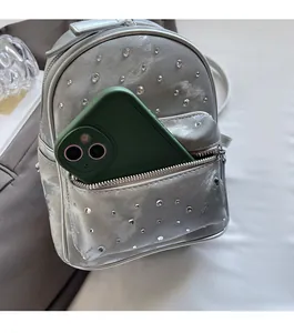 Detail view of silver mini backpack with rhinestone decor and front zipper storage pocket