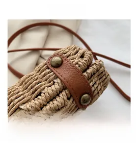 Detail showing the woven texture and metal rivets on the brown leather strap of a saddle bag