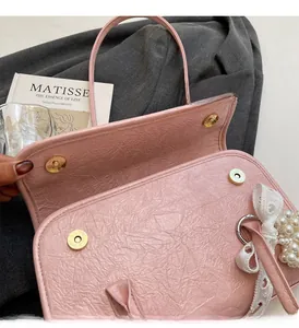 Detailed view of pink pleated handbag with golden magnetic buckles and pearl lace bow